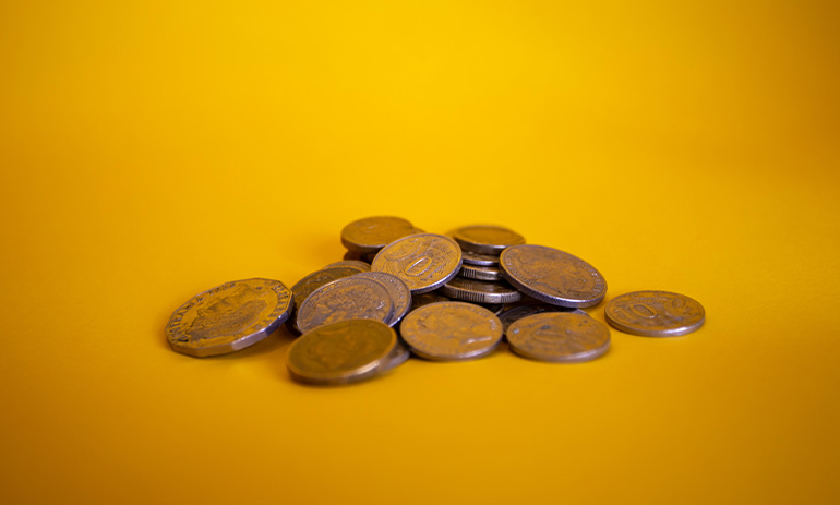 A pile of Australian coins on a yellow surface and background.