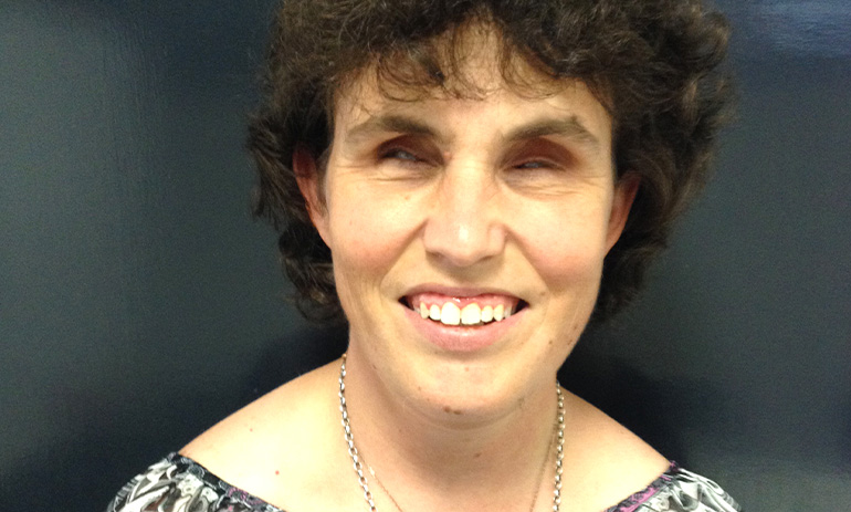 Emma Bennison, a blind lady, smiles at the camera. She has dark curly hair and is wearing a necklace.