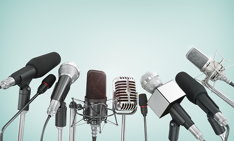 A row of different types of microphones lined up against a blue background.