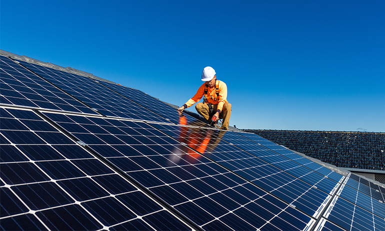 Construction worker installing solar panels on the roof of a building.