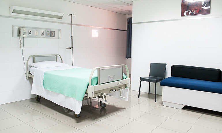 A hospital room with a bed and chairs.
