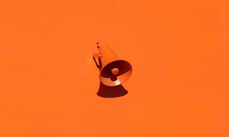 A bright orange background, with a megaphone in the same colour sitting on it.