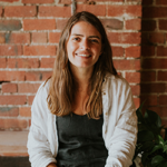 Loretta Bolotin smiling casually in a white shirt against a brick wall.