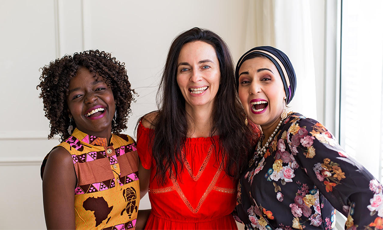 Three diverse women smiling and laughing