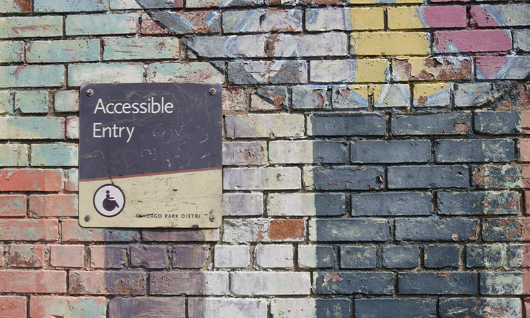 A colourful brick wall with a sign on it that says 'accessible entry'.