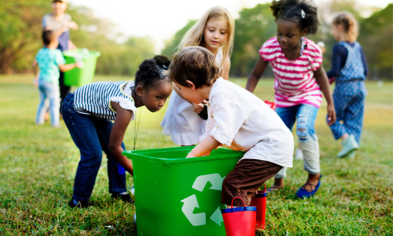 group of kids putting rubbish in a recycling bucket